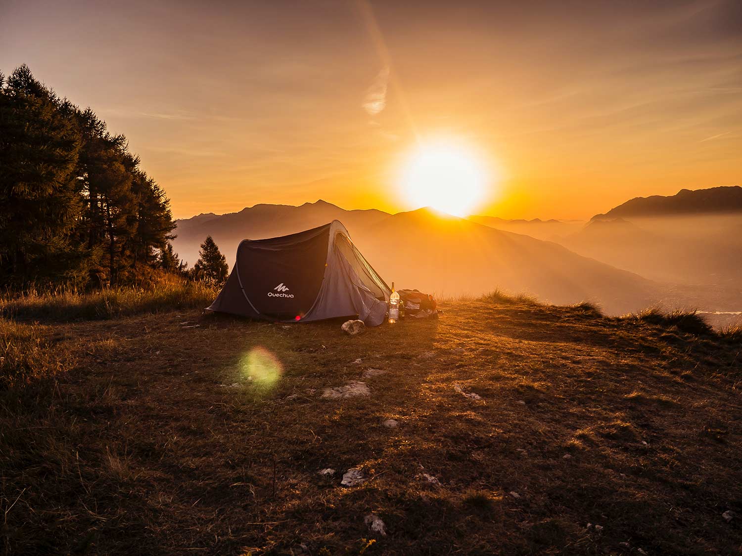 在俯视山和日落的山坡的一个野营的帐篷。