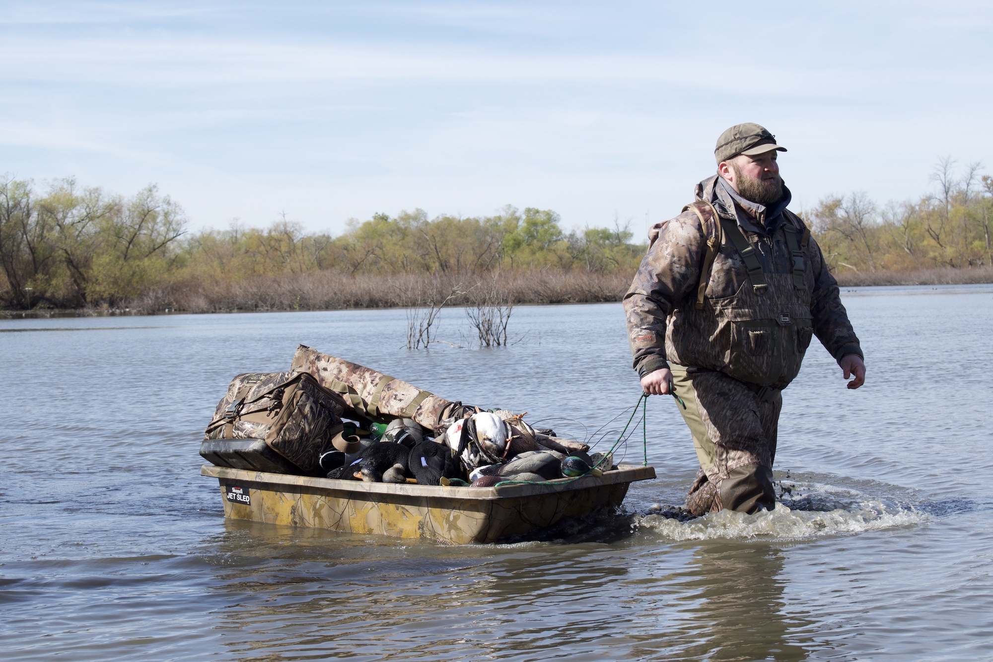 一个男人穿着猎鸭用的最好的水靴在水里拖着装备